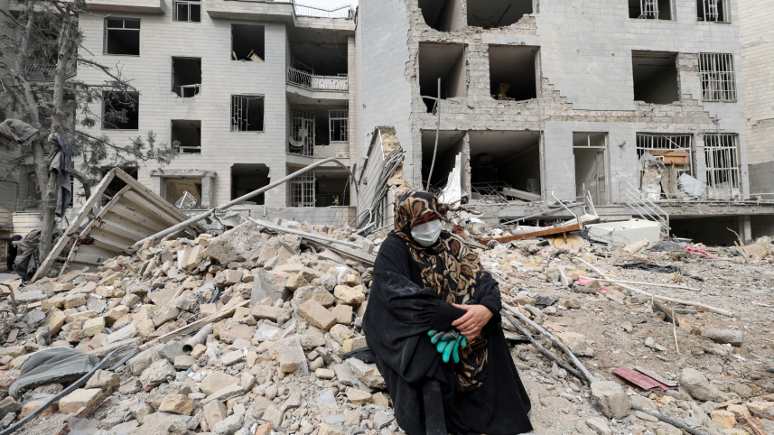 A woman sits outside her destroyed apartment after it was damaged by an airstrike while she was inside, amid the U.S.-Israeli conflict with Iran, in Tehran, Iran, March 12, 2026. Photo: Reuters