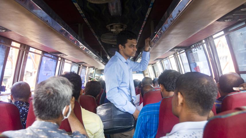 An exhausted person standing in the aisle of a bus. 