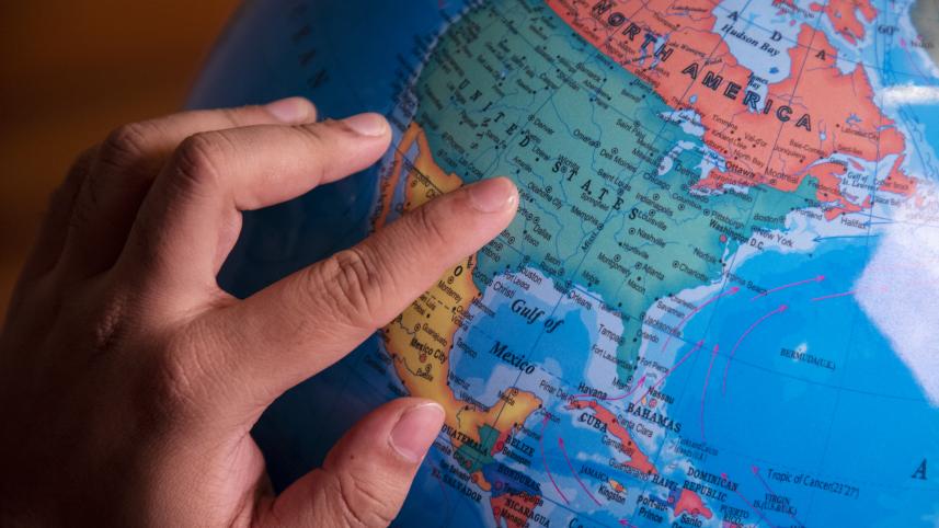 A person with their finger placed on a globe.
