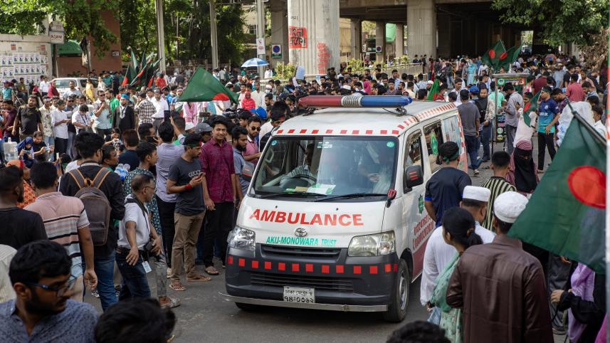 An ambulance driving through a narrow space accommodated by the crowd of protestors   