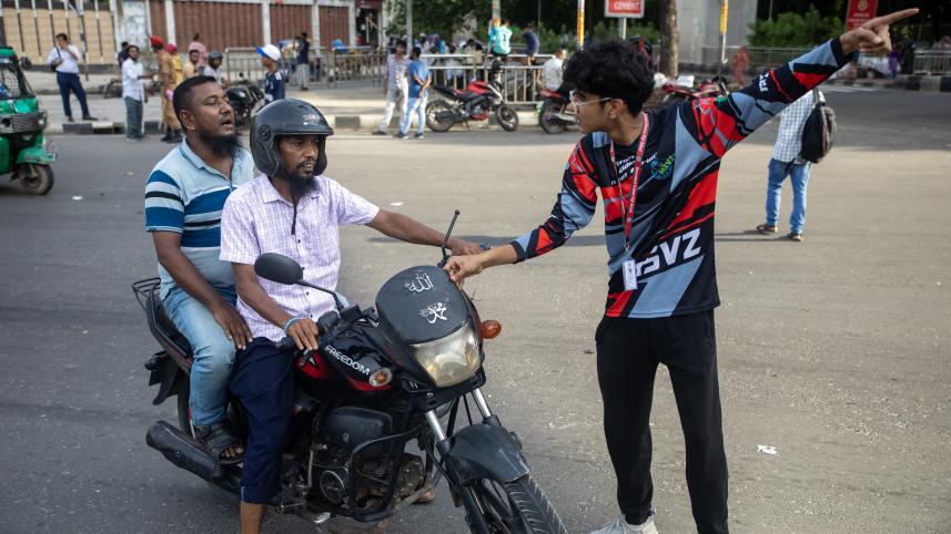 Student directing a bike driver and his passenger. 