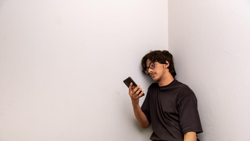 Person leaning against the wall and using their phone. 