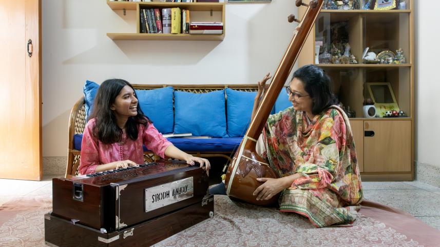 Musician on the left is playing the harmonium while the musician on the left plays the sitar. 