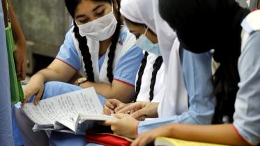 A photo of girls sitting together and reading a textbook