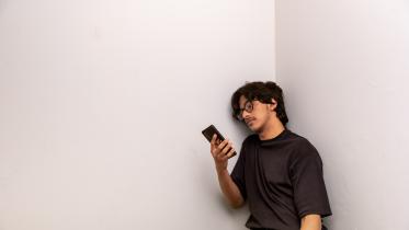 Person leaning against the wall and using their phone. 