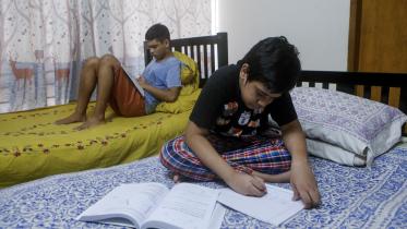 Siblings studying in their separate beds.  