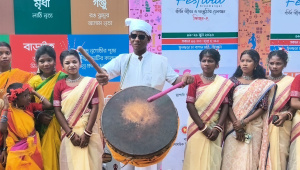 Dressed in traditional white clothing and a turban, Robi Munda plays the nagara at the Harmony Festival