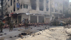 Captured and detained Palestinians sit on a street in Beit Lahia, northern Gaza Strip